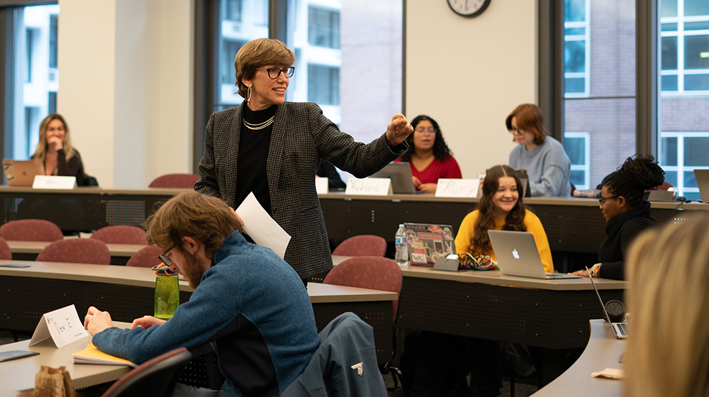 Jenn Griffin with her arm reached out leading a classroom of students